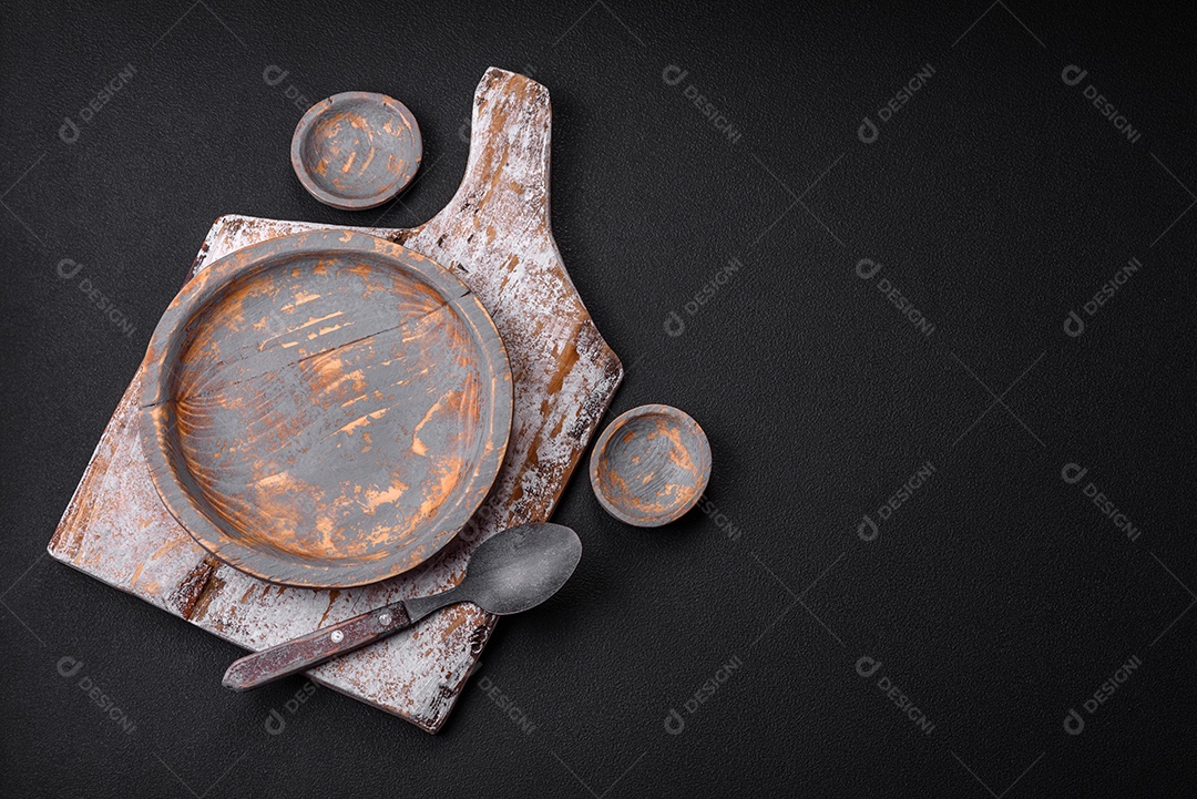 Prato de madeira vazio, faca, garfo e tábua de corte em fundo de concreto texturizado