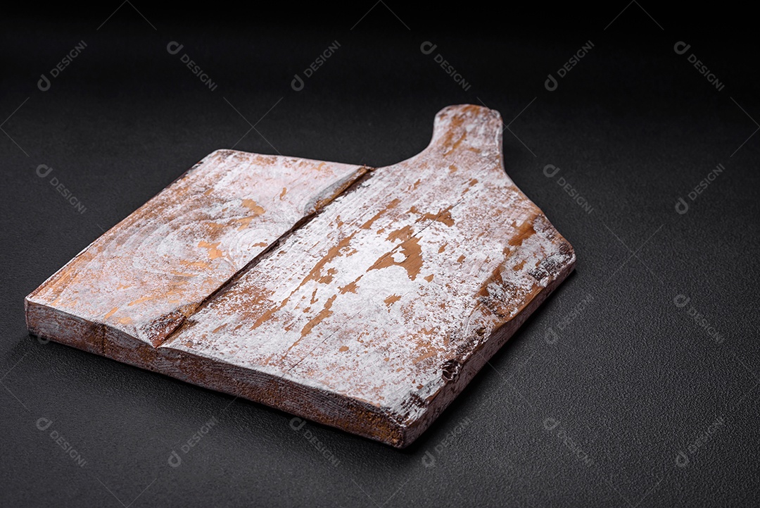 Tábua de corte de madeira vazia com rachaduras e arranhões localizados em um fundo escuro de concreto