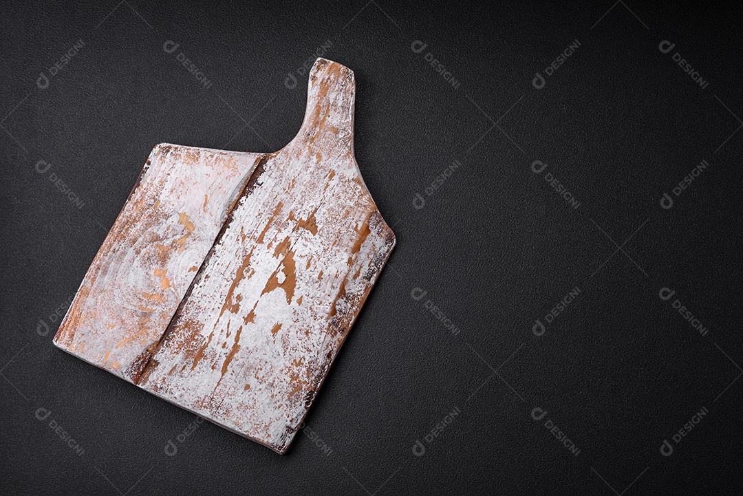 Tábua de corte de madeira vazia com rachaduras e arranhões localizados em um fundo escuro de concreto