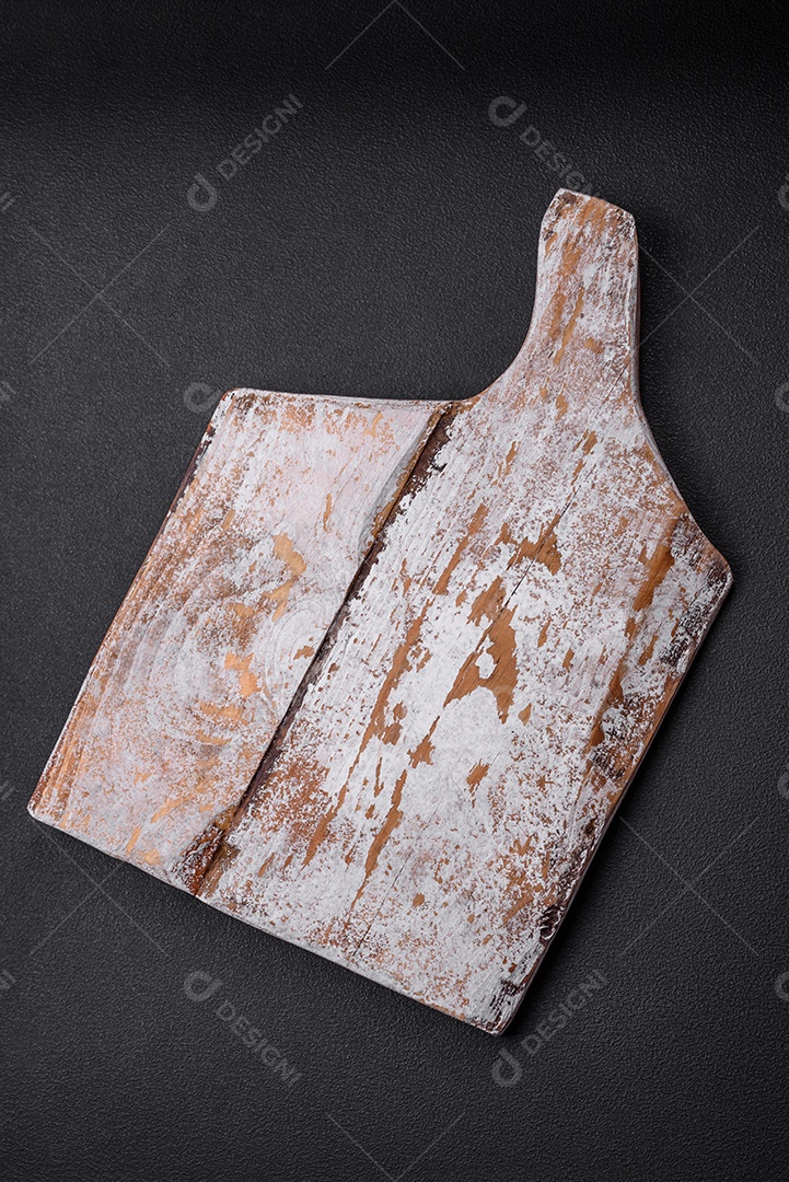 Tábua de corte de madeira vazia com rachaduras e arranhões localizados em um fundo escuro de concreto