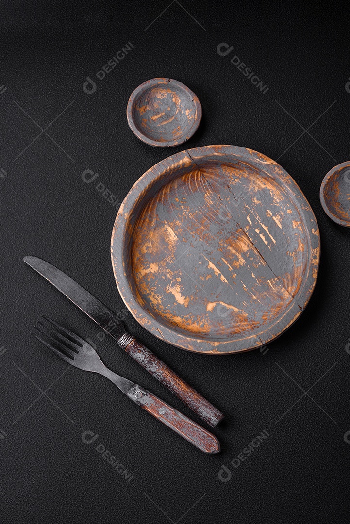 Prato de madeira vazio, faca, garfo e tábua de corte em fundo de concreto texturizado