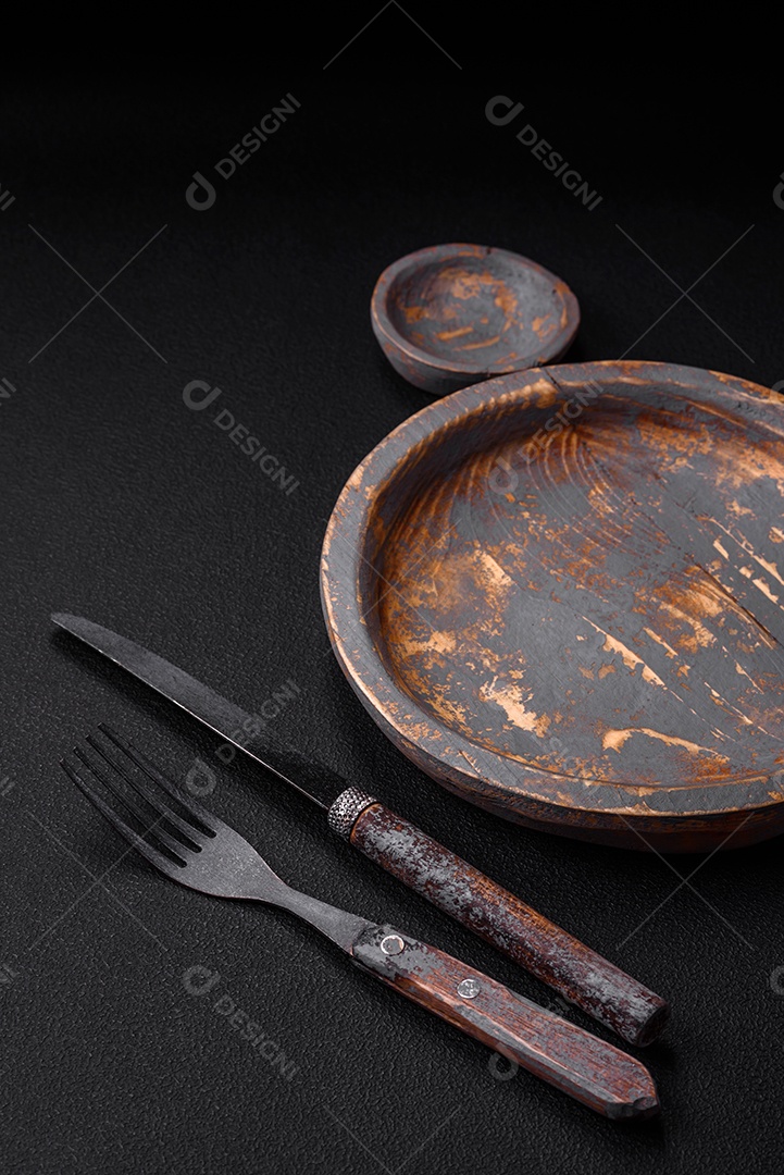 Prato de madeira vazio, faca, garfo e tábua de corte em fundo de concreto texturizado