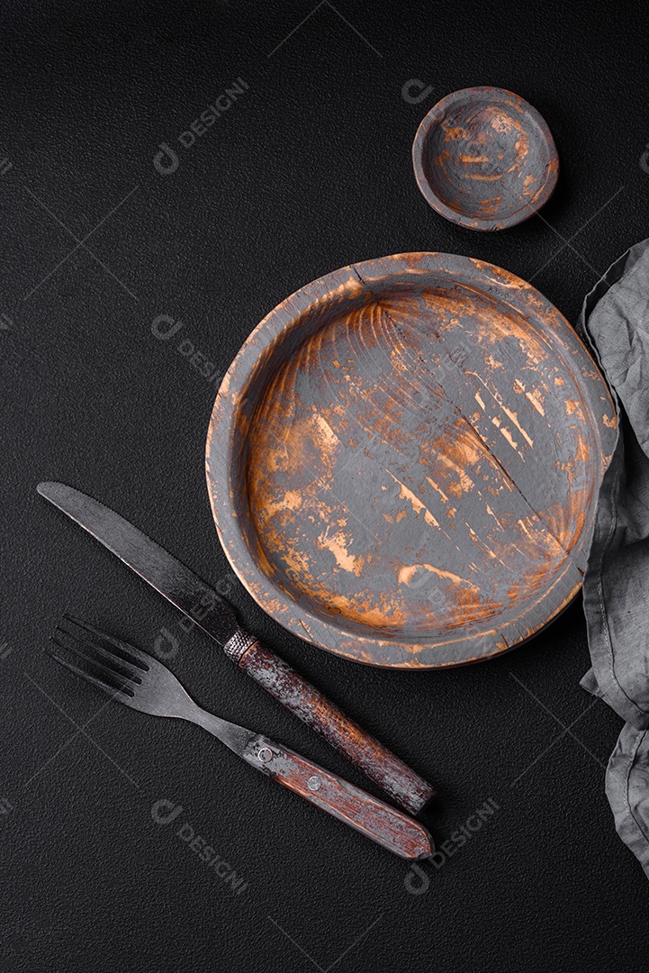 Prato de madeira vazio, faca, garfo e tábua de corte em fundo de concreto texturizado