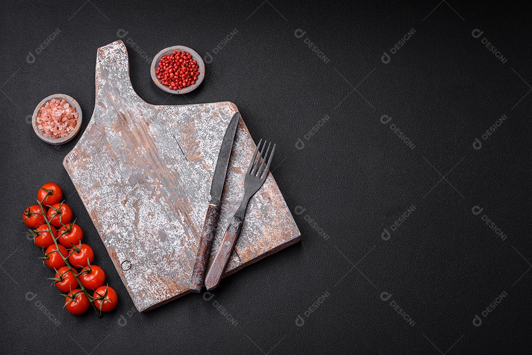 Faca garfo e tábua sal pimenta e outros ingredientes localizados em um fundo de concreto texturizado