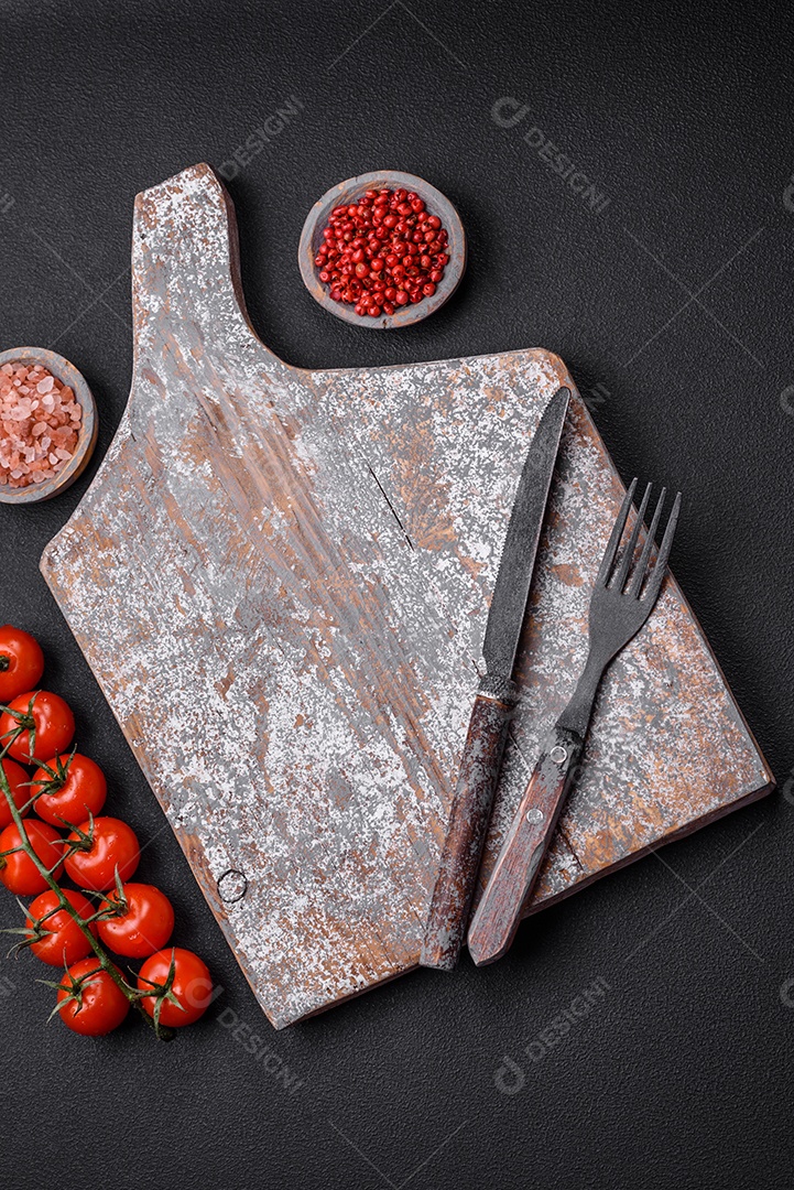 Faca garfo e tábua sal pimenta e outros ingredientes localizados em um fundo de concreto texturizado