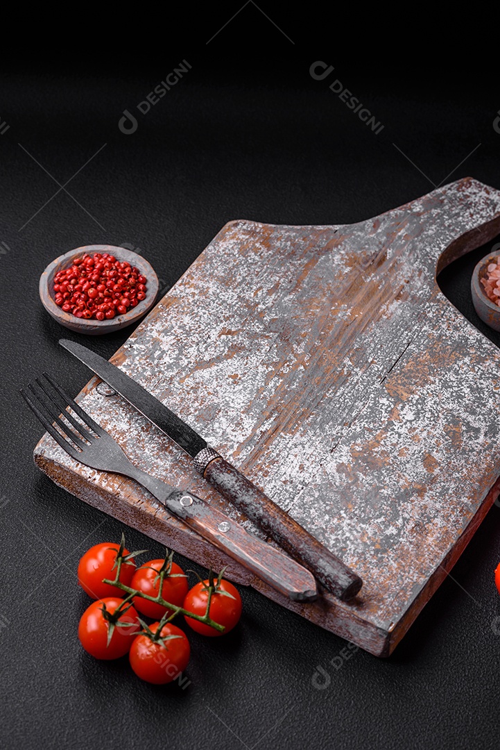 Faca garfo e tábua sal pimenta e outros ingredientes localizados em um fundo de concreto texturizado