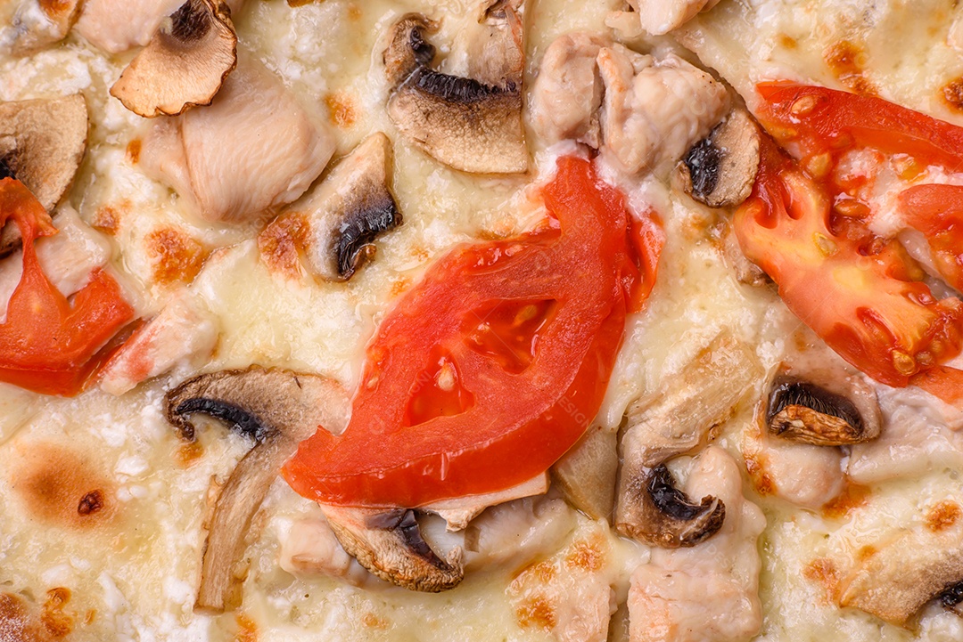 Deliciosa pizza com frango, tomate e queijo com sal e molho sobre um fundo escuro de concreto