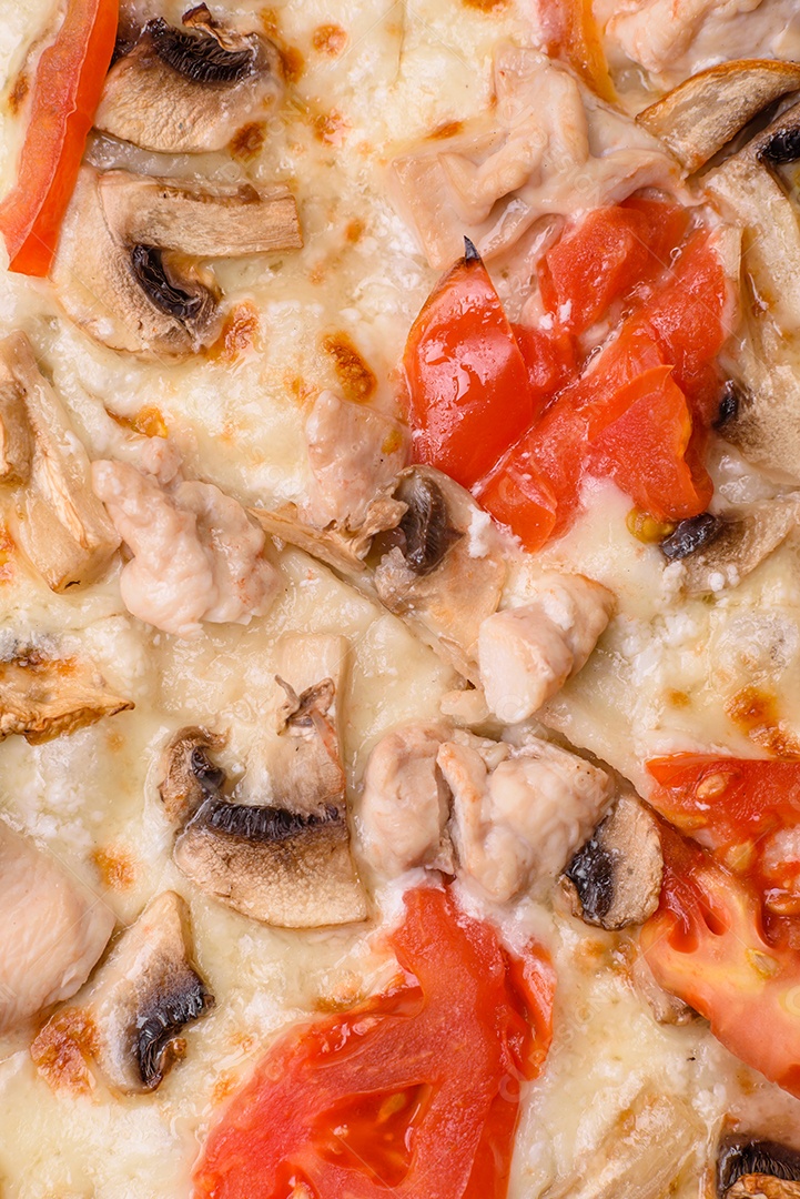 Deliciosa pizza com frango, tomate e queijo com sal e molho sobre um fundo escuro de concreto