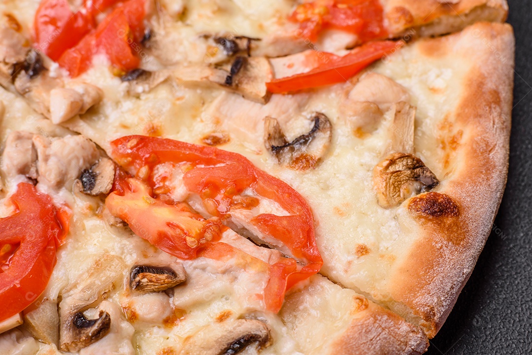 Deliciosa pizza com frango, tomate e queijo com sal e molho sobre um fundo escuro de concreto