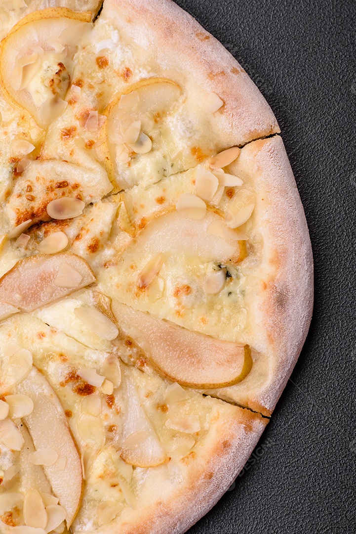 Pizza bávara com enchidos, tomates, queijo, sal e especiarias sobre um fundo escuro de concreto