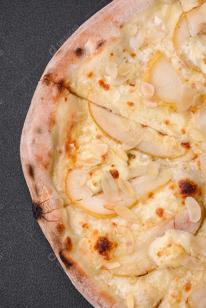 Pizza bávara com enchidos, tomates, queijo, sal e especiarias sobre um fundo escuro de concreto