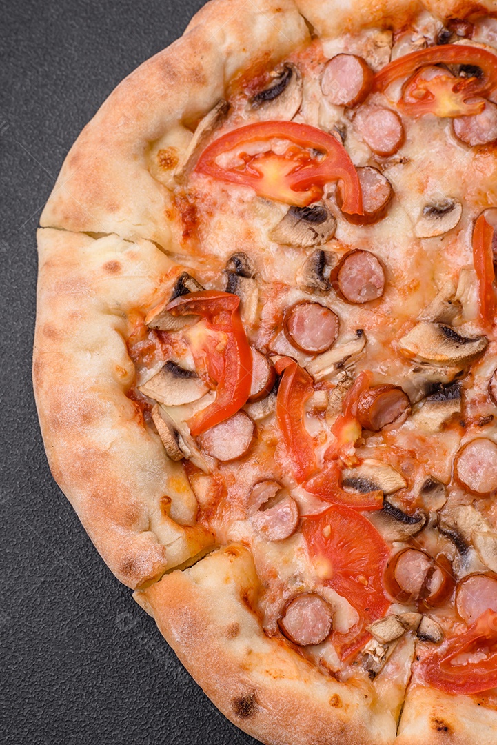 Pizza bávara com enchidos, tomates, queijo, sal e especiarias sobre um fundo escuro de concreto