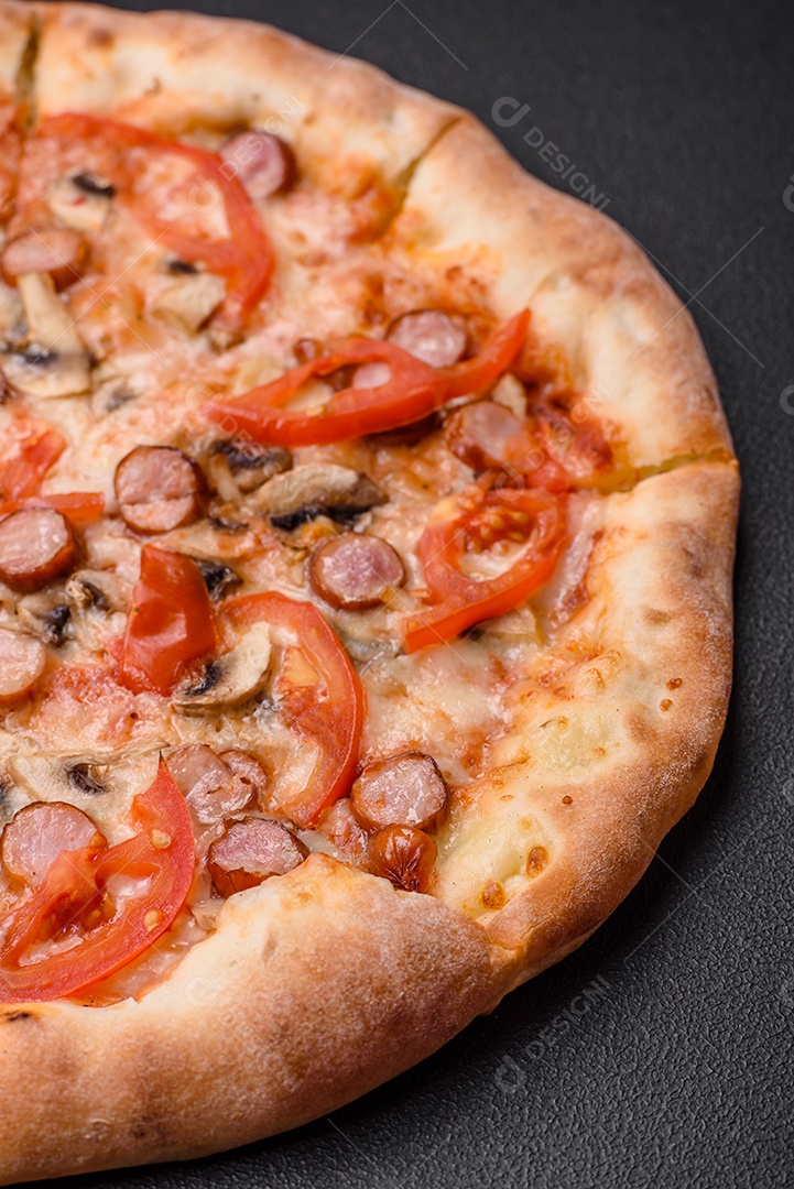 Pizza bávara com enchidos, tomates, queijo, sal e especiarias sobre um fundo escuro de concreto