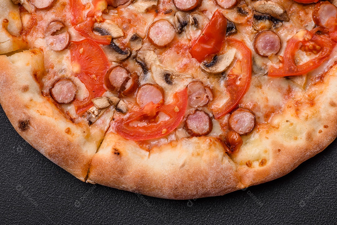Pizza bávara com enchidos, tomates, queijo, sal e especiarias sobre um fundo escuro de concreto