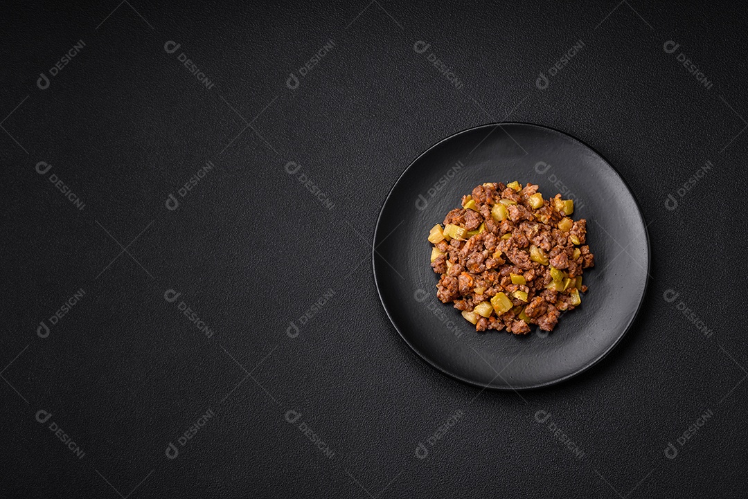 Saboroso prato composto por abobrinha, carne bovina, cogumelos, cebola e alho com sal e especiarias sobre um fundo escuro de concreto