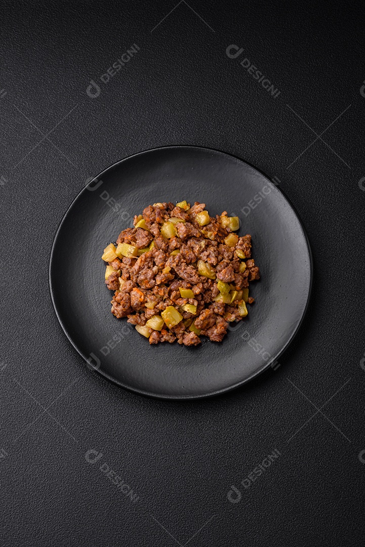 Saboroso prato composto por abobrinha, carne bovina, cogumelos, cebola e alho com sal e especiarias sobre um fundo escuro de concreto