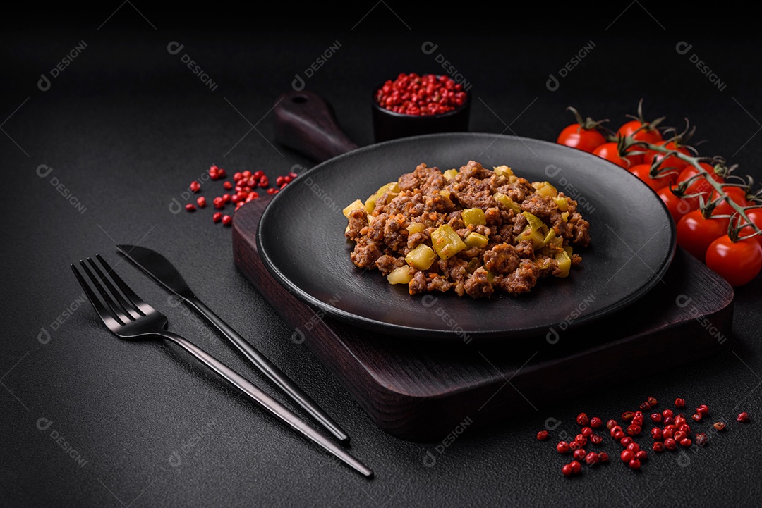 Saboroso prato composto por abobrinha, carne bovina, cogumelos, cebola e alho com sal e especiarias sobre um fundo escuro de concreto