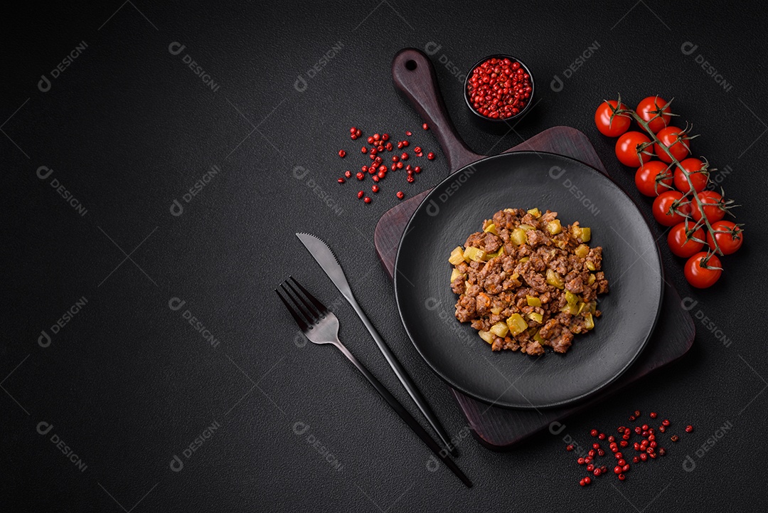 Saboroso prato composto por abobrinha, carne bovina, cogumelos, cebola e alho com sal e especiarias sobre um fundo escuro de concreto