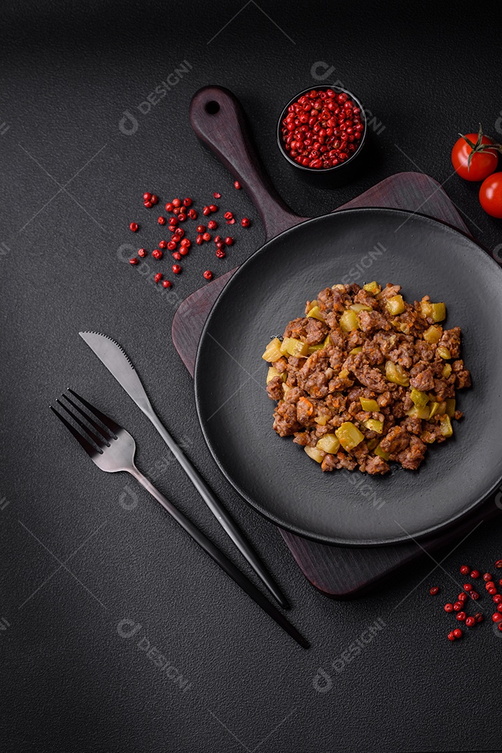 Saboroso prato composto por abobrinha, carne bovina, cogumelos, cebola e alho com sal e especiarias sobre um fundo escuro de concreto