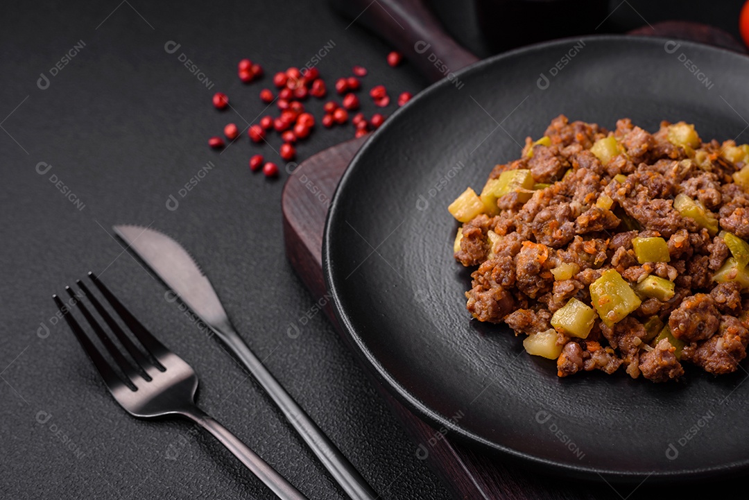 Saboroso prato composto por abobrinha, carne bovina, cogumelos, cebola e alho com sal e especiarias sobre um fundo escuro de concreto