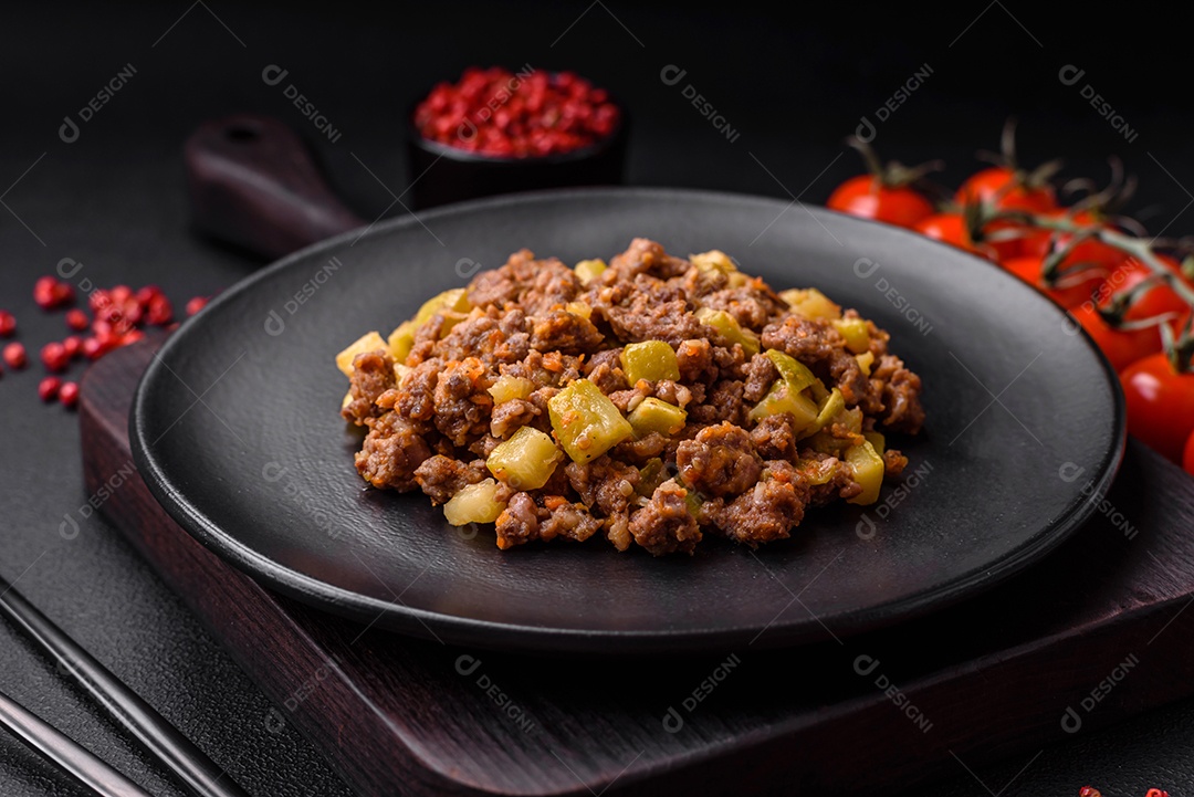 Saboroso prato composto por abobrinha, carne bovina, cogumelos, cebola e alho com sal e especiarias sobre um fundo escuro de concreto