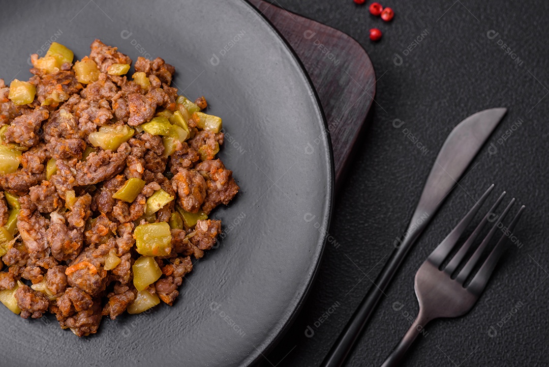 Saboroso prato composto por abobrinha, carne bovina, cogumelos, cebola e alho com sal e especiarias sobre um fundo escuro de concreto