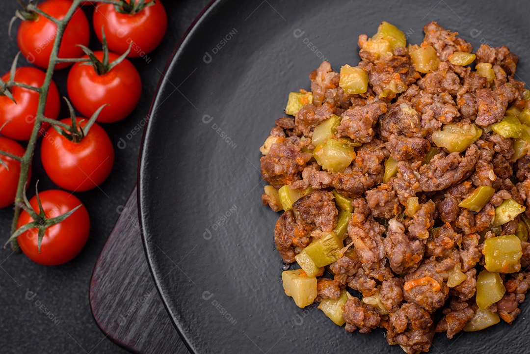 Saboroso prato composto por abobrinha, carne bovina, cogumelos, cebola e alho com sal e especiarias sobre um fundo escuro de concreto