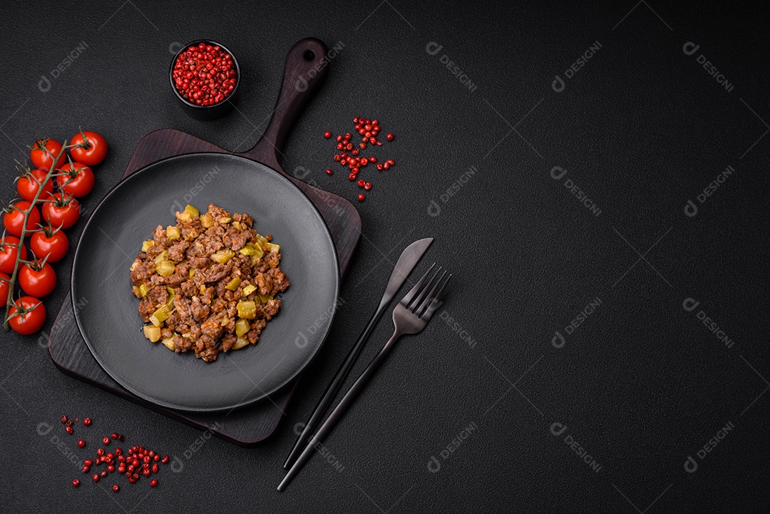 Saboroso prato composto por abobrinha, carne bovina, cogumelos, cebola e alho com sal e especiarias sobre um fundo escuro de concreto