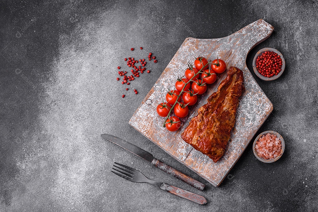 Deliciosas costelas de porco grelhadas ou defumadas com sal, especiarias e ervas em fundo de concreto texturizado