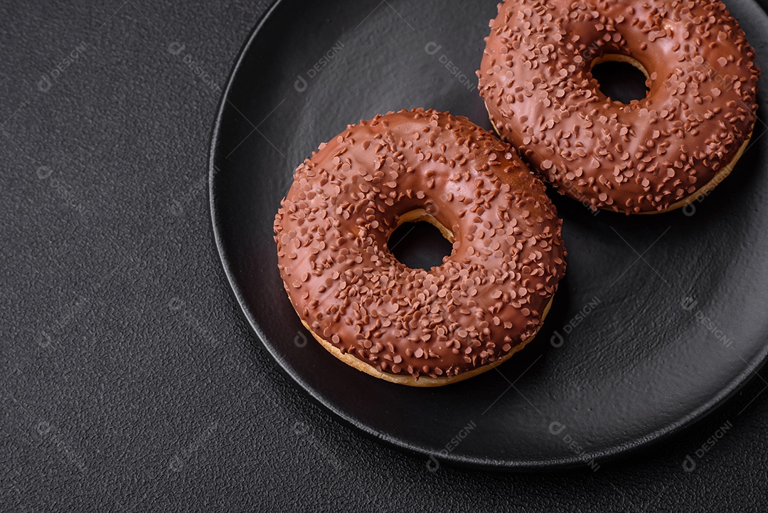 Delicioso donut com cobertura de chocolate polvilhado com pedaços de chocolate sobre um fundo escuro de concreto