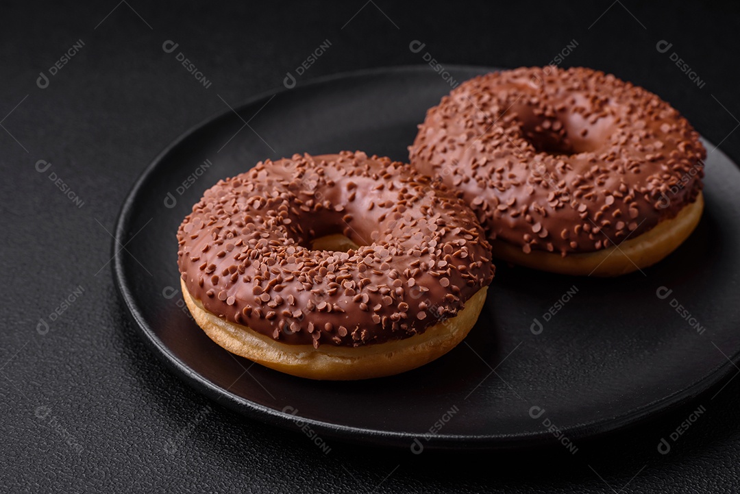 Delicioso donut com cobertura de chocolate polvilhado com pedaços de chocolate sobre um fundo escuro de concreto