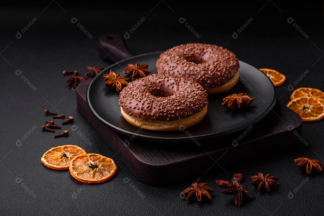 Delicioso donut com cobertura de chocolate polvilhado com pedaços de chocolate sobre um fundo escuro de concreto