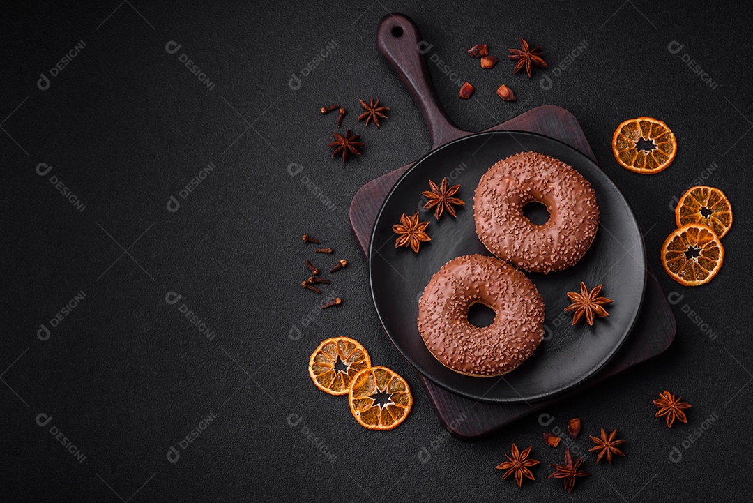 Delicioso donut com cobertura de chocolate polvilhado com pedaços de chocolate sobre um fundo escuro de concreto