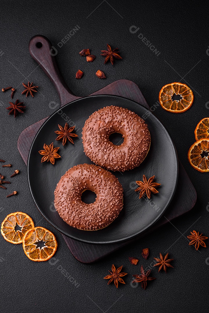 Delicioso donut com cobertura de chocolate polvilhado com pedaços de chocolate sobre um fundo escuro de concreto