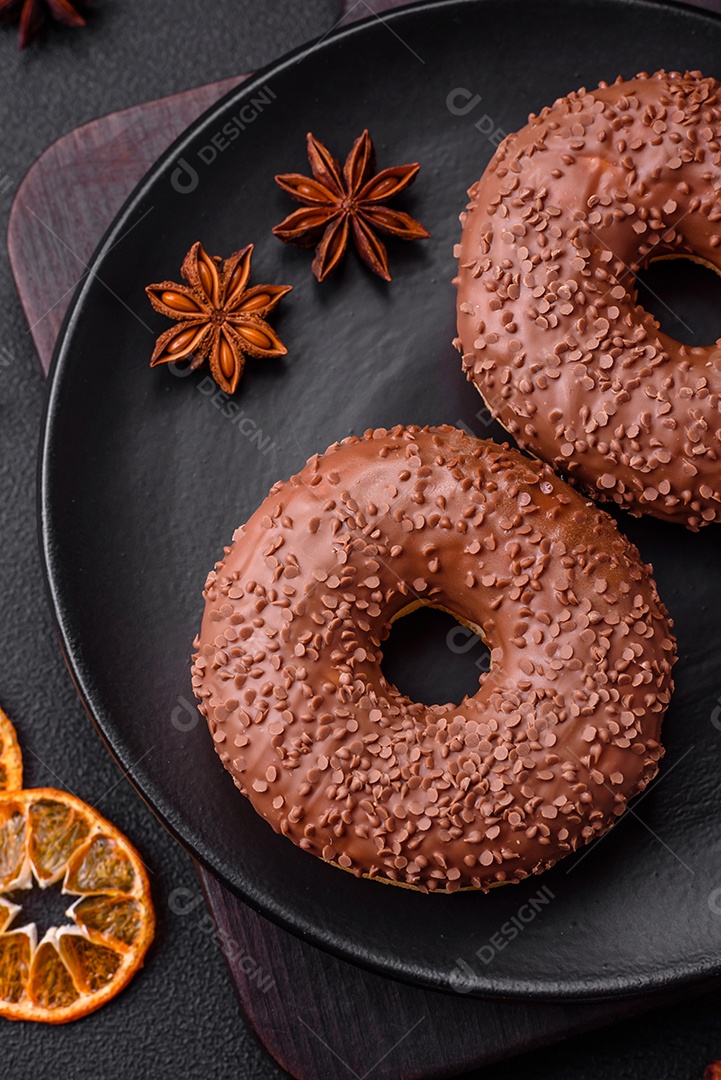 Delicioso donut com cobertura de chocolate polvilhado com pedaços de chocolate sobre um fundo escuro de concreto