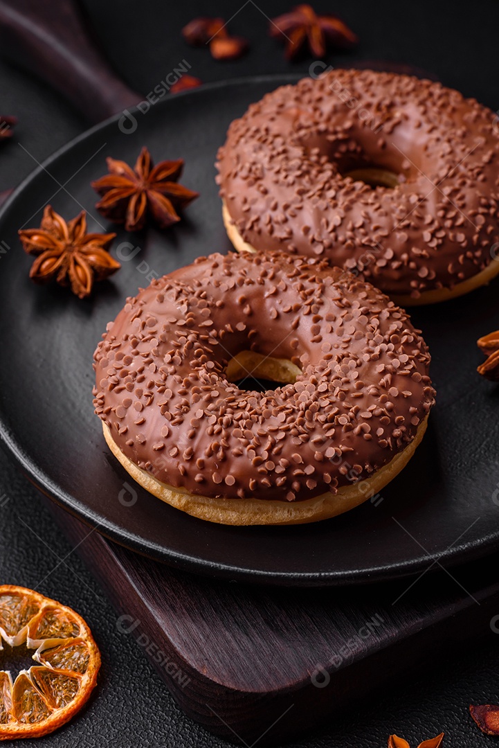 Delicioso donut com cobertura de chocolate polvilhado com pedaços de chocolate sobre um fundo escuro de concreto