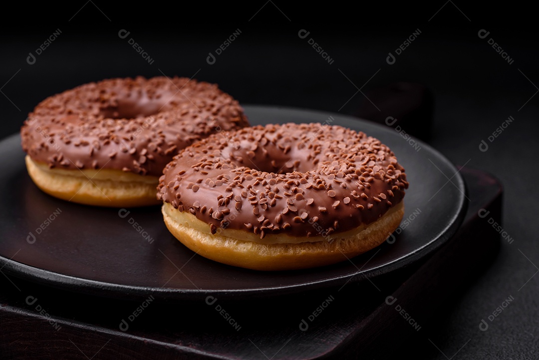 Delicioso donut com cobertura de chocolate polvilhado com pedaços de chocolate sobre um fundo escuro de concreto