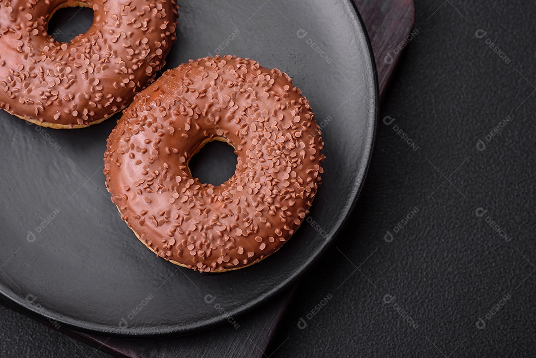 Delicioso donut com cobertura de chocolate polvilhado com pedaços de chocolate sobre um fundo escuro de concreto