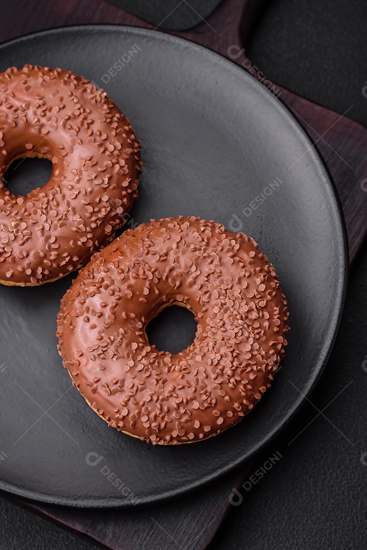 Delicioso donut com cobertura de chocolate polvilhado com pedaços de chocolate sobre um fundo escuro de concreto