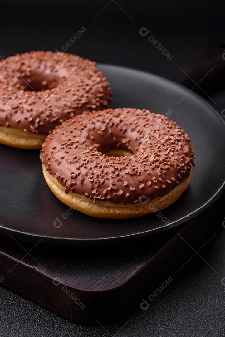 Delicioso donut com cobertura de chocolate polvilhado com pedaços de chocolate sobre um fundo escuro de concreto