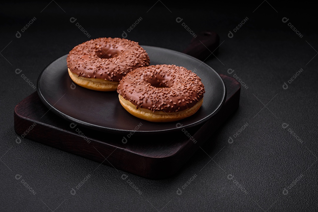 Delicioso donut com cobertura de chocolate polvilhado com pedaços de chocolate sobre um fundo escuro de concreto