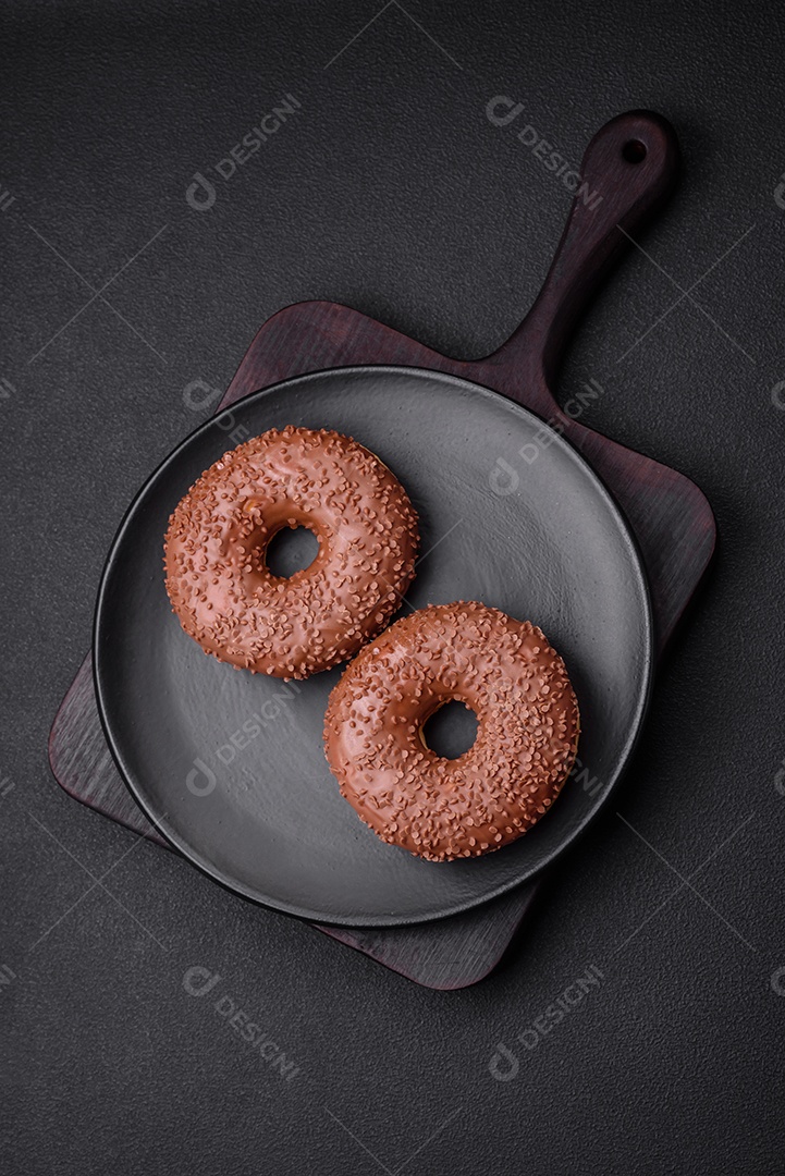 Delicioso donut com cobertura de chocolate polvilhado com pedaços de chocolate sobre um fundo escuro de concreto