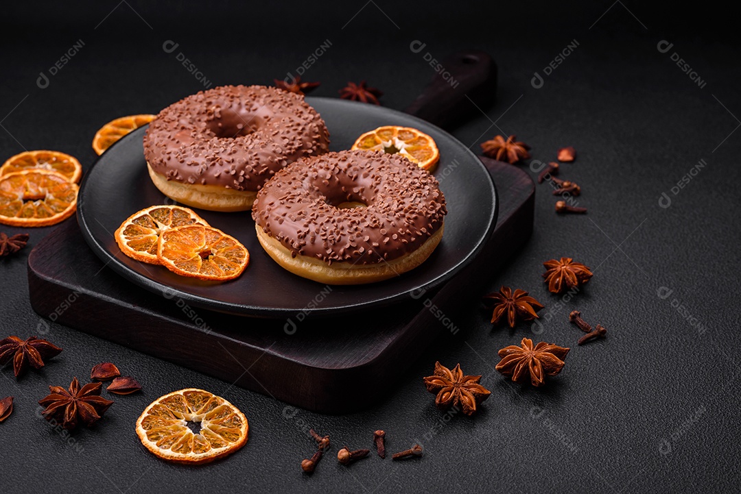 Delicioso donut com cobertura de chocolate polvilhado com pedaços de chocolate sobre um fundo escuro de concreto