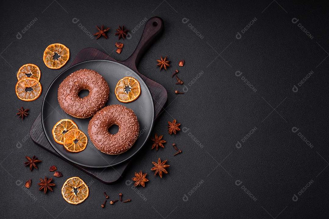 Delicioso donut com cobertura de chocolate polvilhado com pedaços de chocolate sobre um fundo escuro de concreto