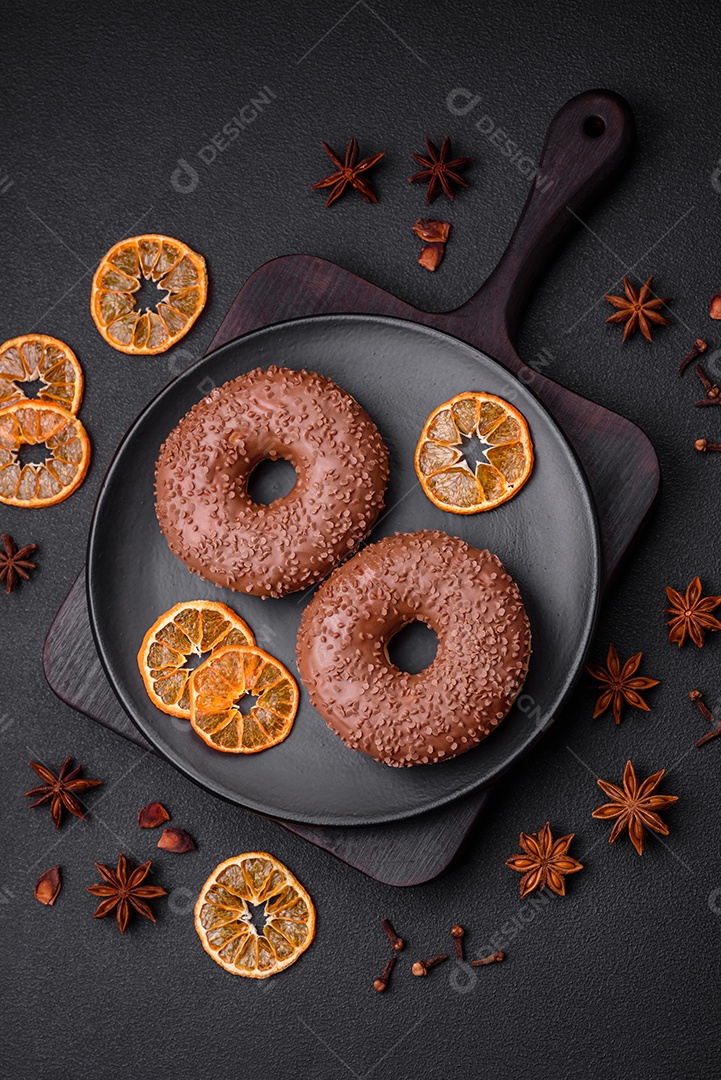 Delicioso donut com cobertura de chocolate polvilhado com pedaços de chocolate sobre um fundo escuro de concreto