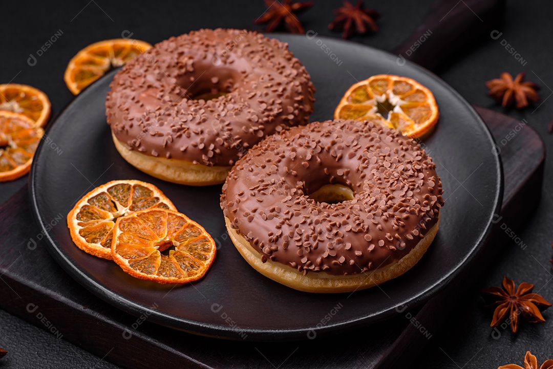 Delicioso donut com cobertura de chocolate polvilhado com pedaços de chocolate sobre um fundo escuro de concreto