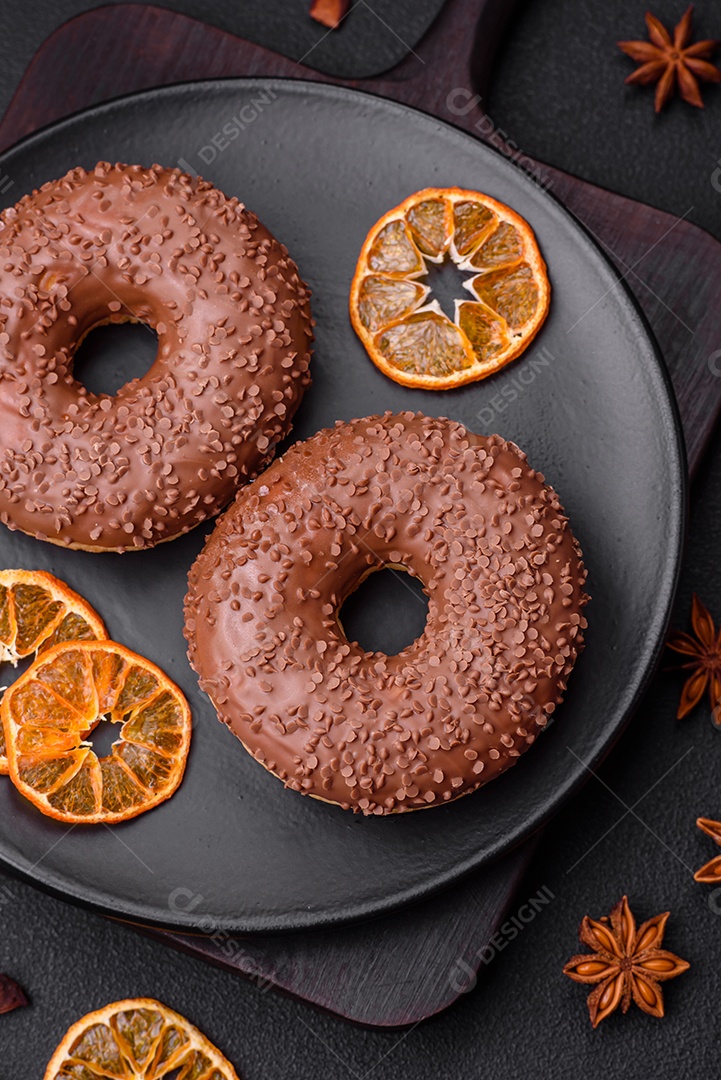 Delicioso donut com cobertura de chocolate polvilhado com pedaços de chocolate sobre um fundo escuro de concreto