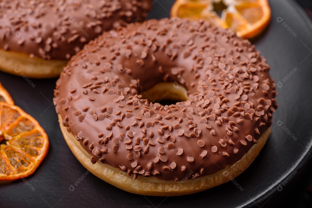 Delicioso donut com cobertura de chocolate polvilhado com pedaços de chocolate sobre um fundo escuro de concreto
