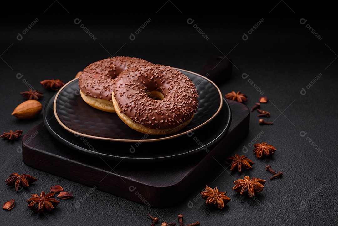 Delicioso donut com cobertura de chocolate polvilhado com pedaços de chocolate sobre um fundo escuro de concreto
