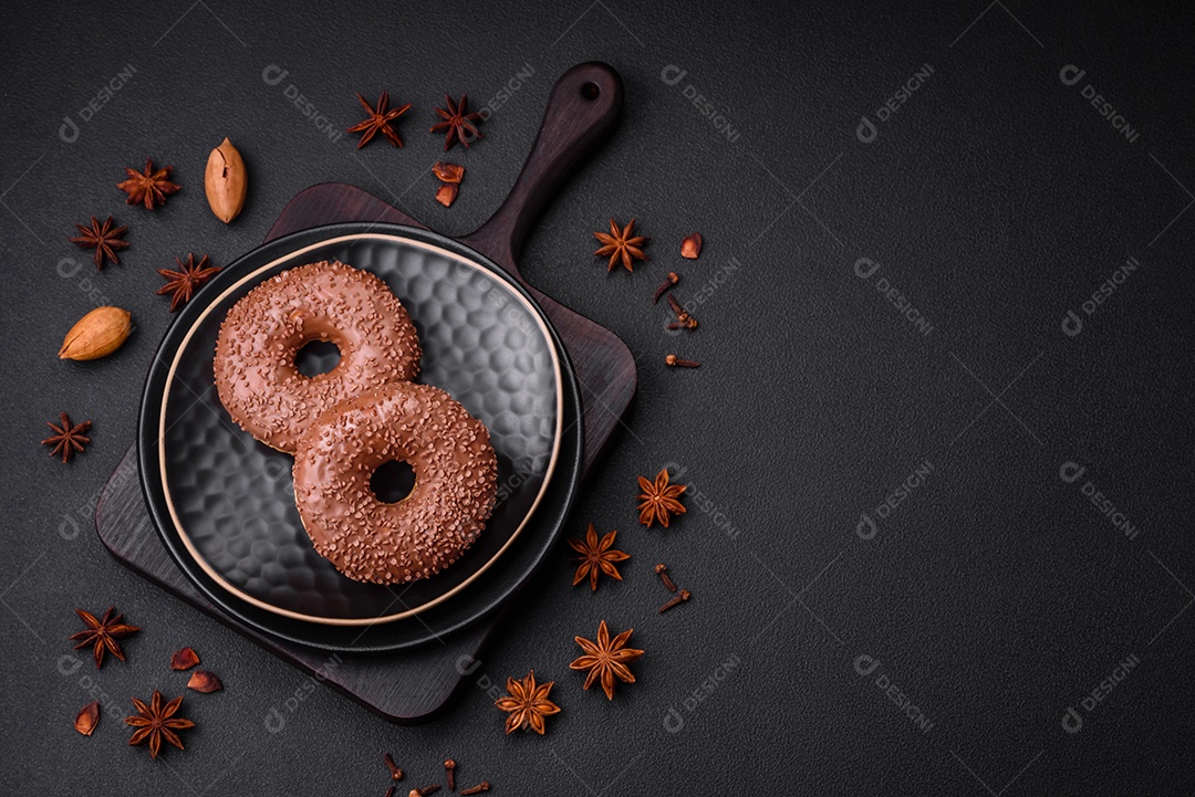 Delicioso donut com cobertura de chocolate polvilhado com pedaços de chocolate sobre um fundo escuro de concreto